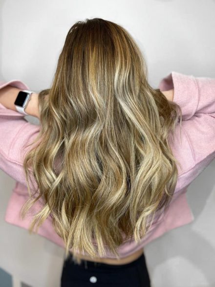 woman standing lifting hair with blonde balayage highlights