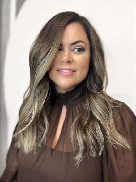Brunette woman smiling with brunette hair and blonde balayage highlights