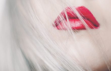 Close up of pof woman's face with platinum blonde hair and red lick stick on full lips.
